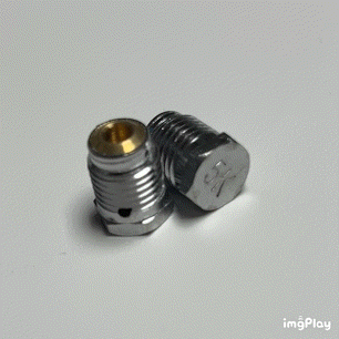 Two metallic screws, one with a brass-colored inner lining, lay on a white surface.